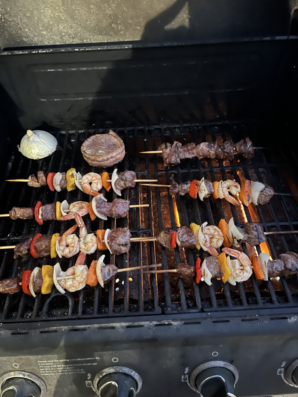 Meat, shrimp, and vegetable skewers cooking on Robert's grill
