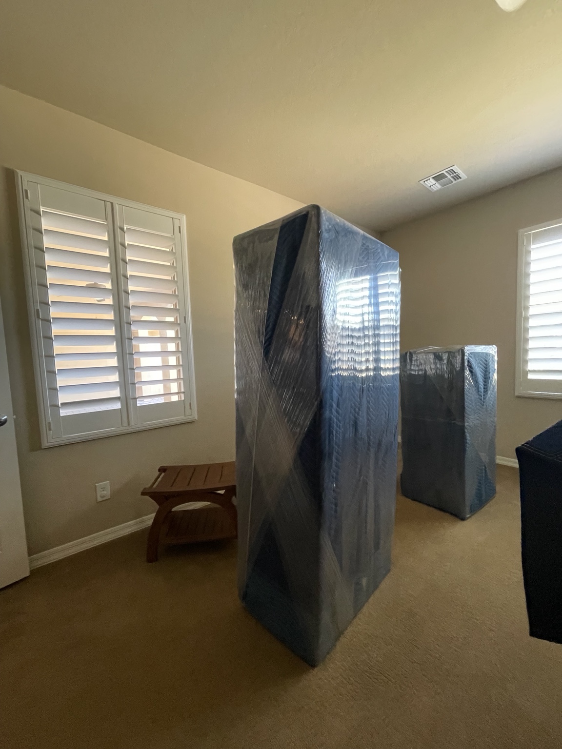 Tall furniture wrapped in protective moving blankets and stretch wrap